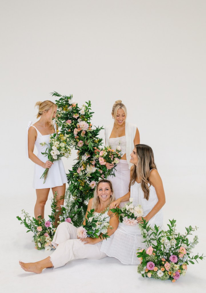 Florist team smiling next to flower arrangements